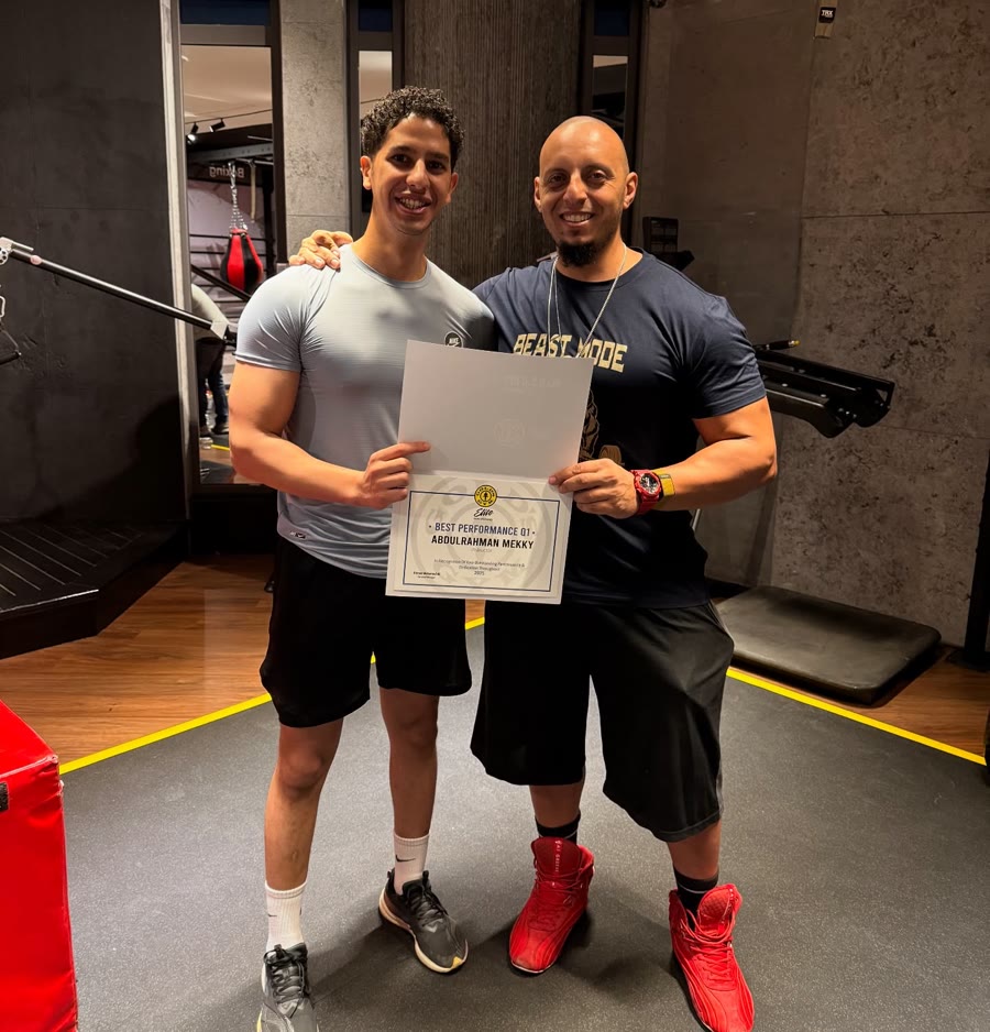 Meky and his manager smiling in the gym, holding his Gold's Gym Elite Best Performance Q1 certificate