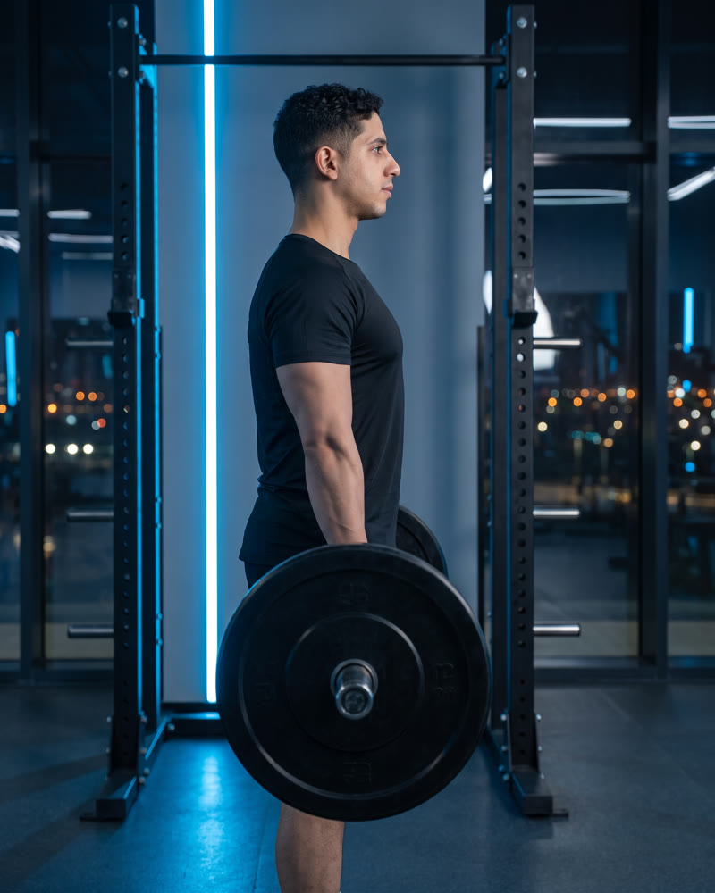 Meky standing tall at the top of a barbell deadlift